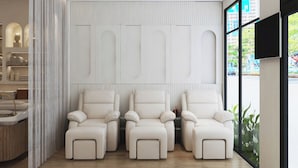 A modern spa room with three reclining chairs, a massage table, and a large window offering a view of the city. - Riverside Mini Hotel Grand World (Phu Quoc)