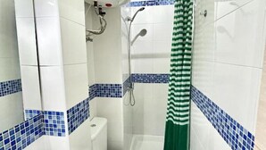 Baño con inodoro, lavamanos, ducha y cortina de ducha verde a rayas.