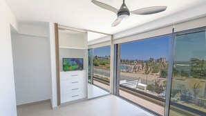 A modern bedroom with a large sliding glass door leading to a balcony, a ceiling fan, and a flat-screen TV on a white cabinet. - Protaras Holiday Villa Ti39 (Paralimni)