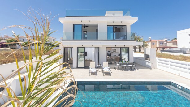 A modern two-story house with a swimming pool, outdoor seating, and a view of the surrounding area. - Protaras Holiday Villa Ti39 (Paralimni)