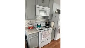A kitchen with a white stove, a microwave above it, and a refrigerator to the right. - Peaceful Comfort Home ideal for work trips and vacation. (Sanford)