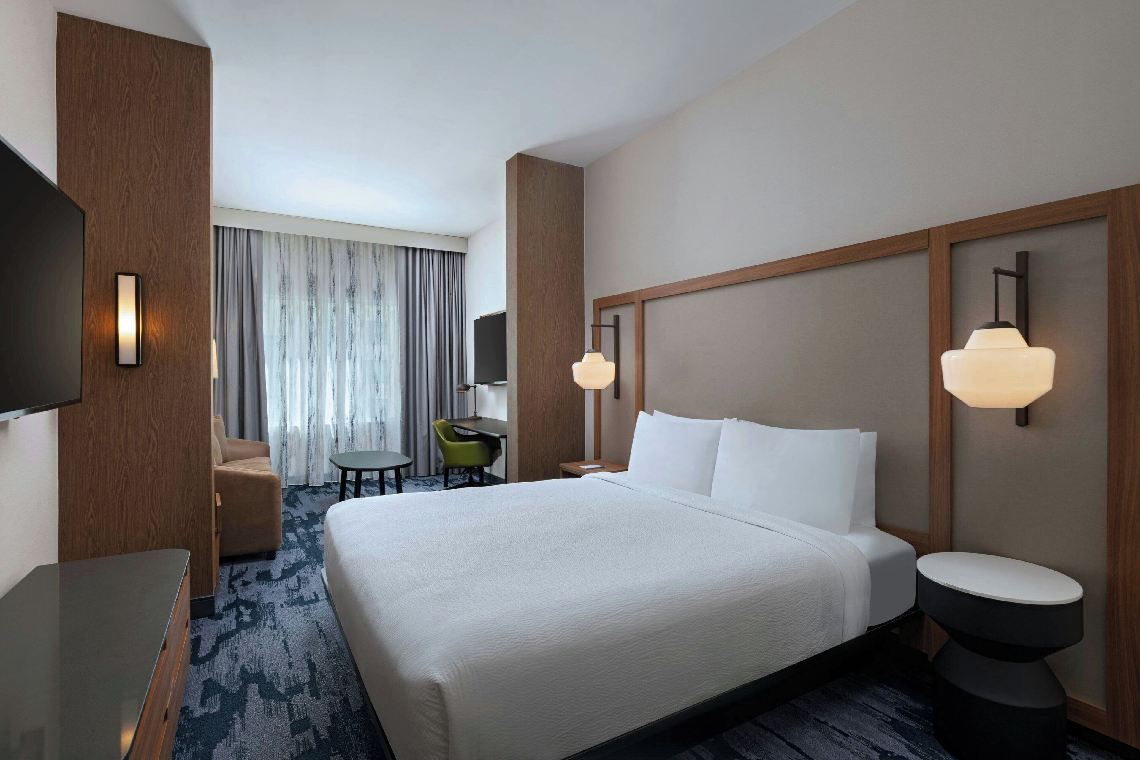 Une chambre d’hôtel avec un grand lit, un bureau, une chaise, une télévision et une salle de bain.