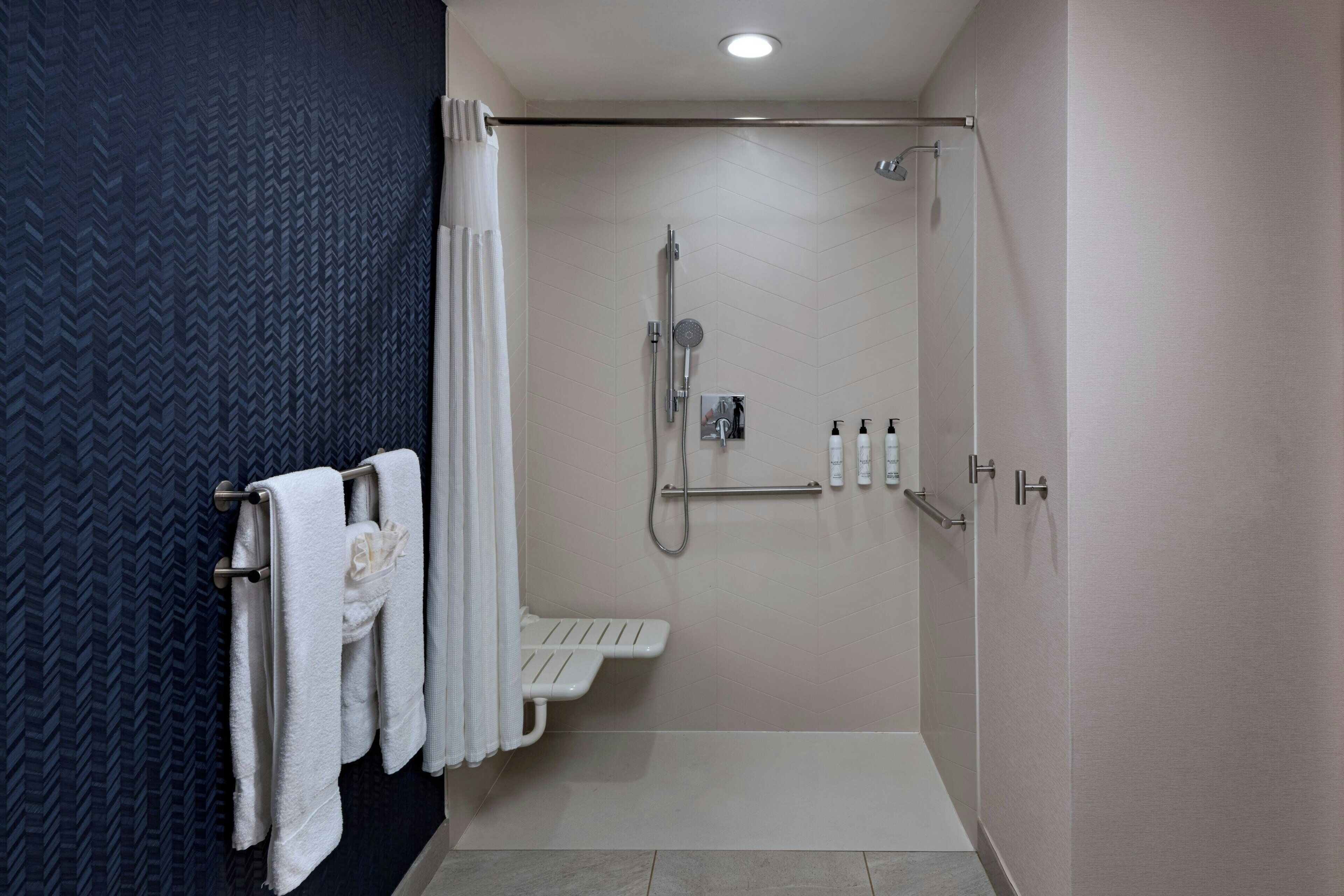 Une salle de bain moderne équipée d’une douche, d’un porte-serviettes et de toilettes.
