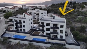 A modern apartment complex with multiple buildings, a swimming pool, and a view of the surrounding landscape. - Cozy Loft Studio With Rooftop, Seaview & Pool (Okrug)