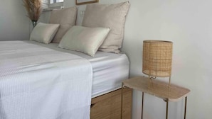 A bedroom with a bed, pillows, a vase with dried flowers, and a wicker lamp on a side table. - Cozy Loft Studio With Rooftop, Seaview & Pool (Okrug)