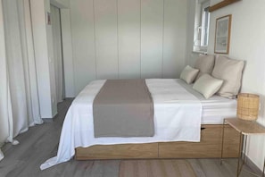 Una camera da letto ordinata con un letto, cuscini, un comodino e un cesto di vimini.