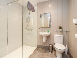 A modern bathroom with a glass-enclosed shower, a white sink, a toilet, and a mirror above the sink. - Beech Lodge (Preston)