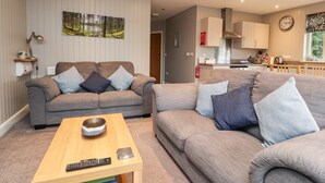 Un salon moderne avec deux canapés, une table basse et une cuisine en arrière-plan.
