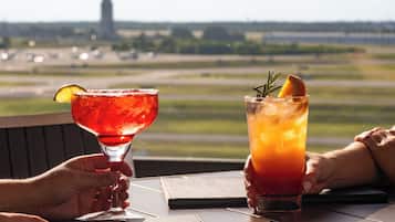 Two drinks on a table with a view of a runway and a tower in the background.