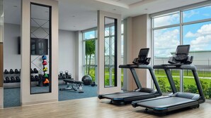 Een moderne sportschool met loopbanden, krachttoestellen en een grote spiegel.