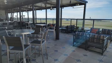 Un patio exterior con baldosas hexagonales, mobiliario de metal y vista a un campo de golf.