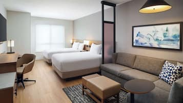 Ett hotellrum med en säng, en soffa, ett skrivbord och en stol.