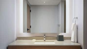 A modern bathroom with a large mirror, a sink, and a towel rack.