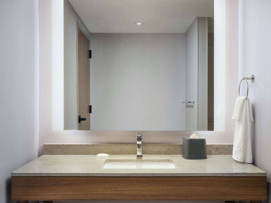 A modern bathroom with a large mirror, a sink, and a towel rack.