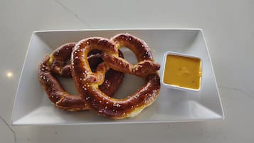 A plate with a pretzel and a small bowl of mustard.