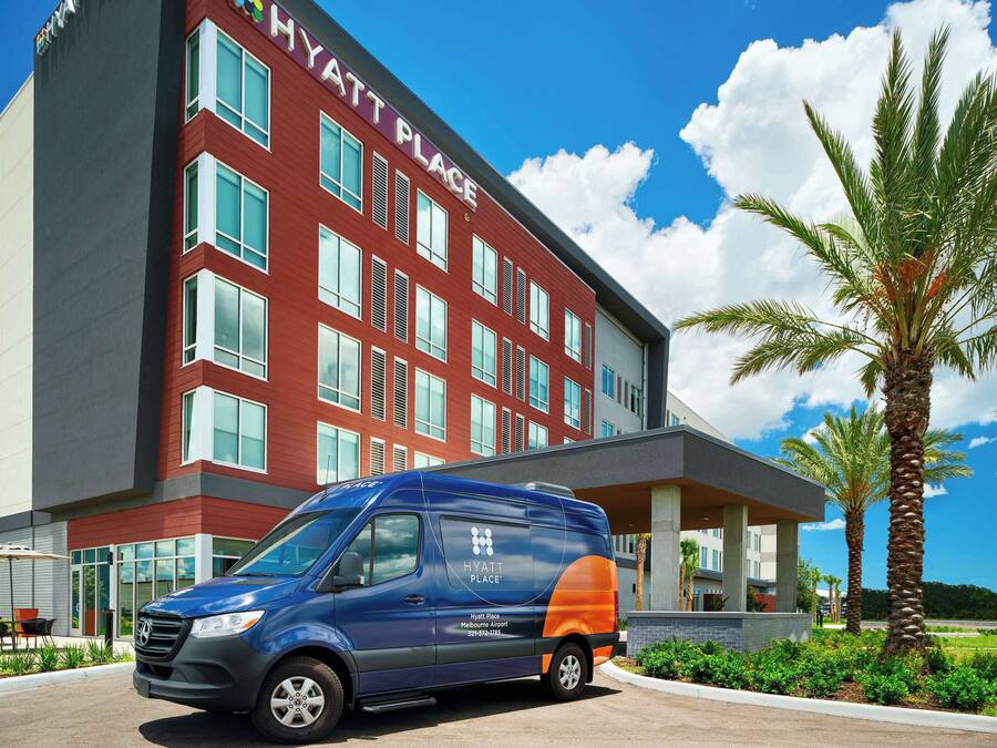 A blue and orange van parked in front of a red and grey building with the sign "Hyatt Place".