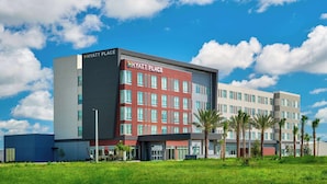 Een modern hotel met een rode en grijze gevel, meerdere verdiepingen en een plat dak.