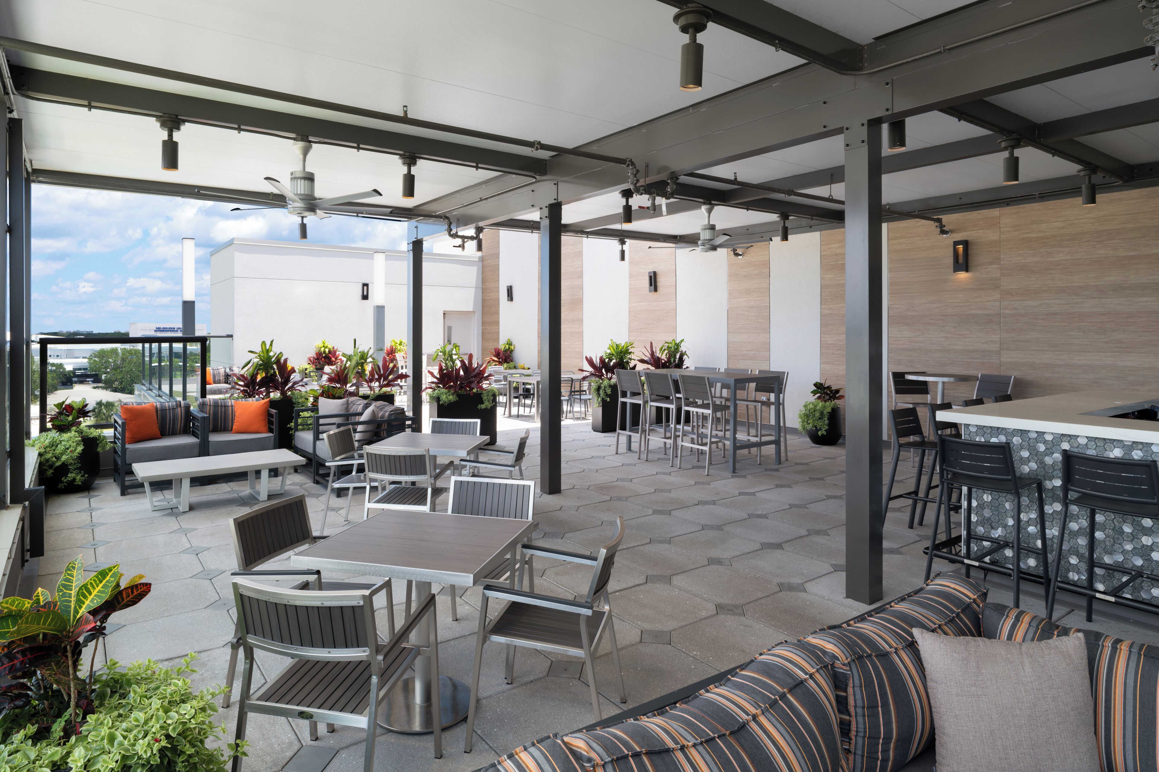 Un espacio al aire libre con patio, asientos, mesas y una barra.