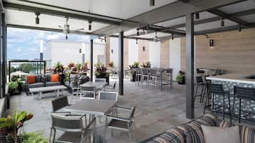 Un espacio al aire libre con patio, asientos, mesas y una barra.