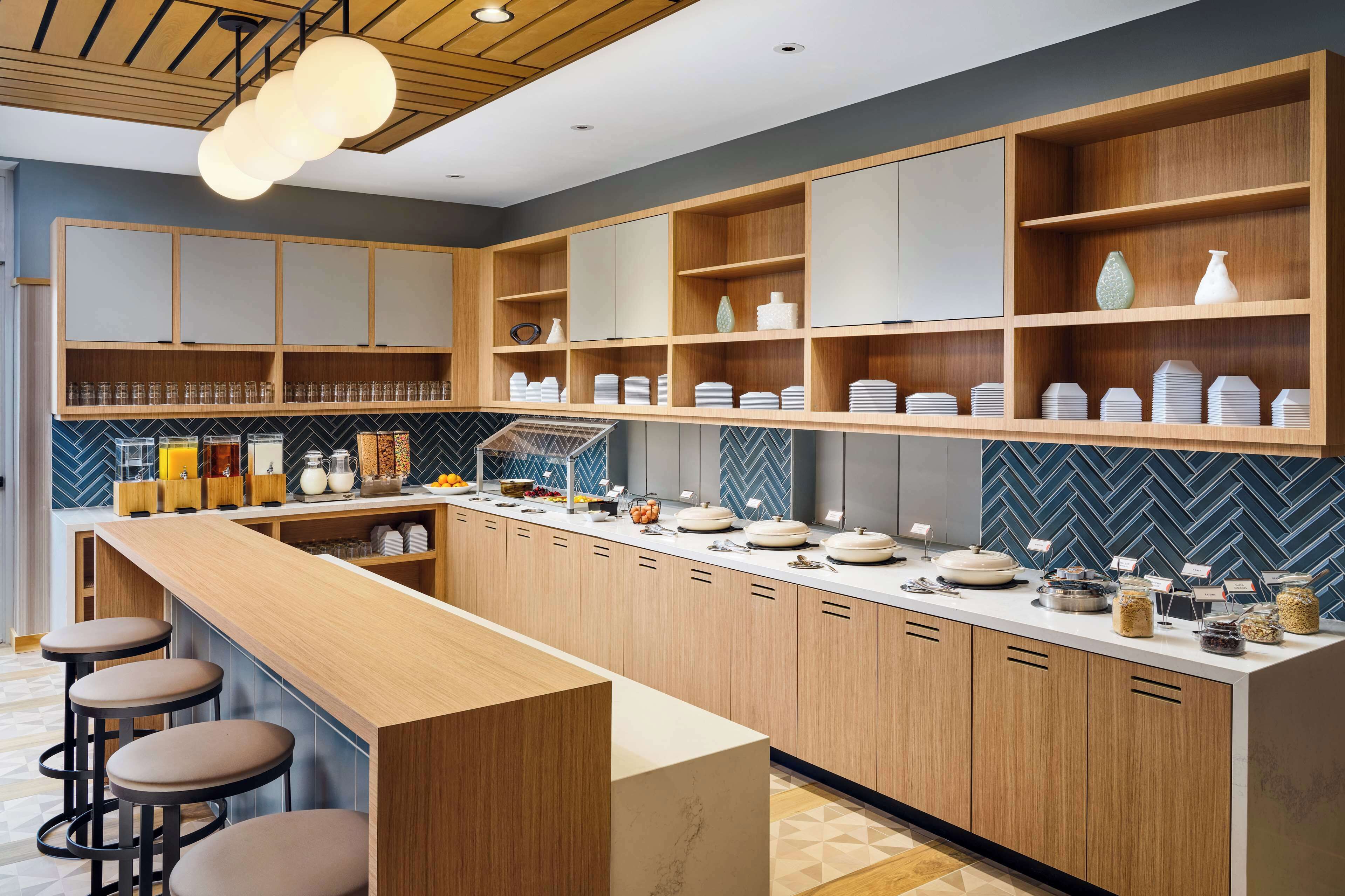 A modern kitchen with wooden cabinets, a marble countertop, and bar stools.