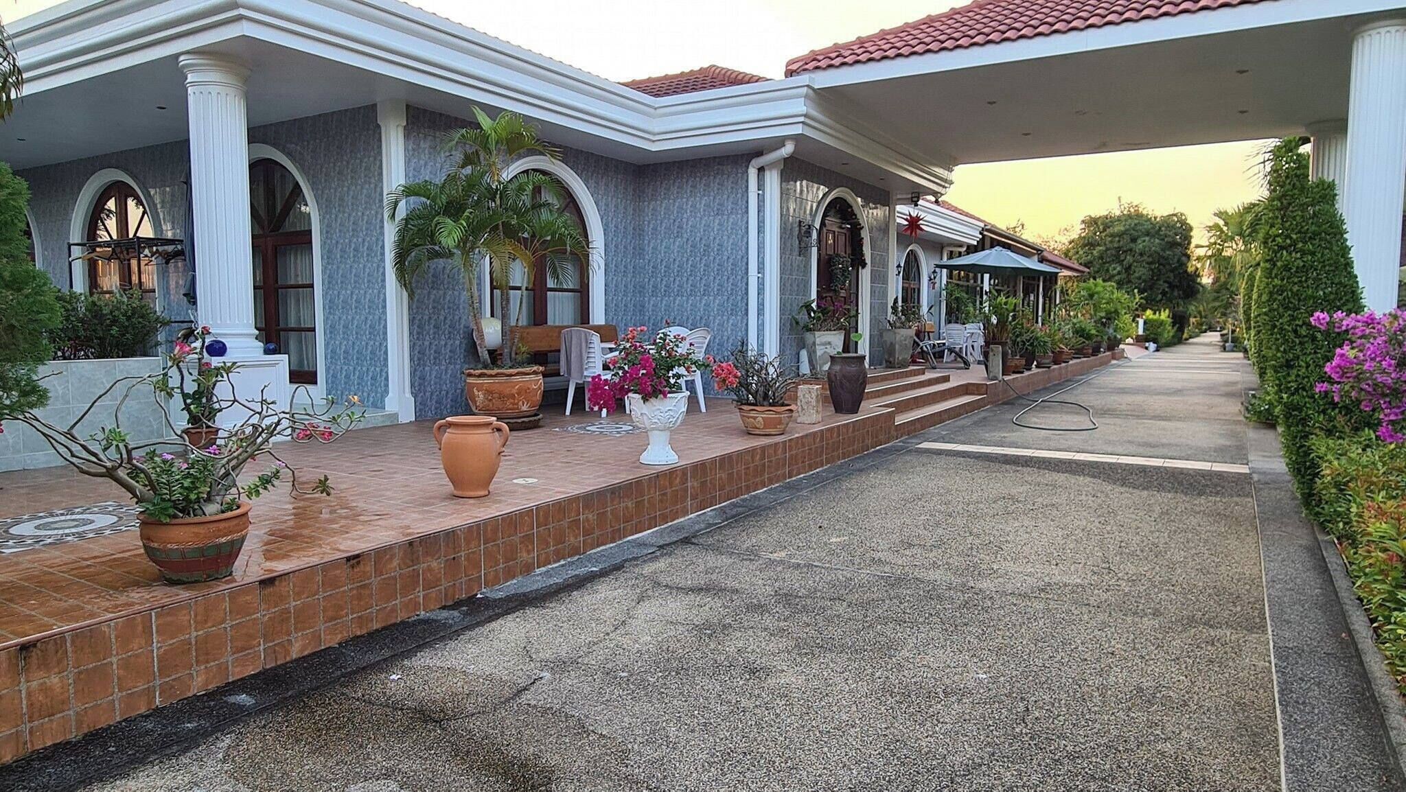 A covered outdoor area with a tiled floor, potted plants, and outdoor furniture.