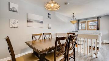 A dining area with a wooden table and chairs, a hanging light fixture, and artwork on the walls.
