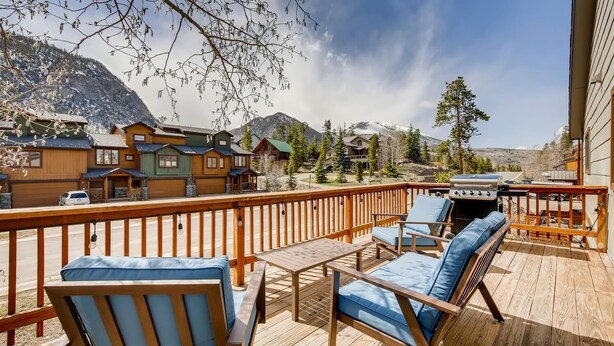A wooden deck with outdoor furniture, a barbecue grill, and a view of mountain houses. - Mount Royal Condos #501 2 Bedroom Condo by RedAwning (Frisco)