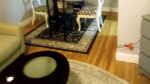Un comedor con una mesa redonda y cuatro sillas, una alfombra pequeña y un ventilador de techo.