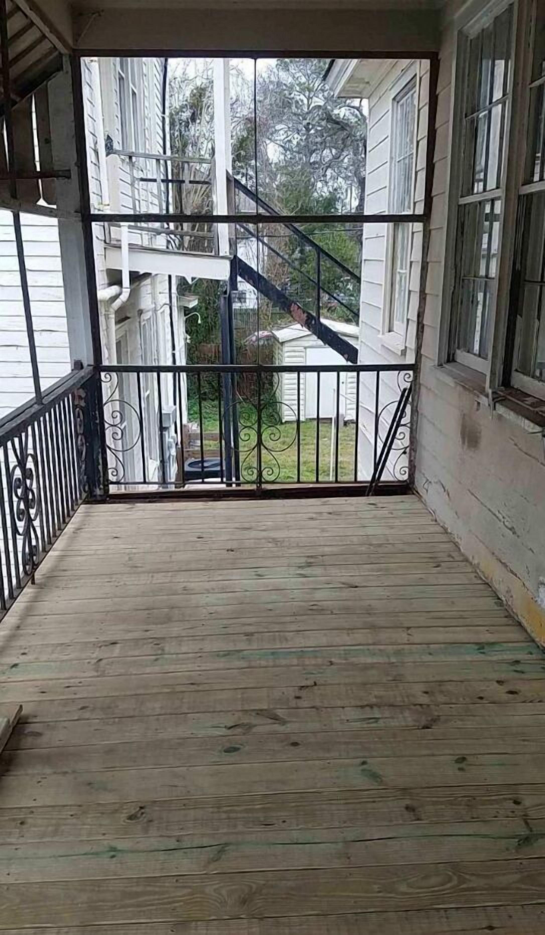 Eine überdachte Holzterrasse mit Metallgeländer, die zu einer Treppe führt.