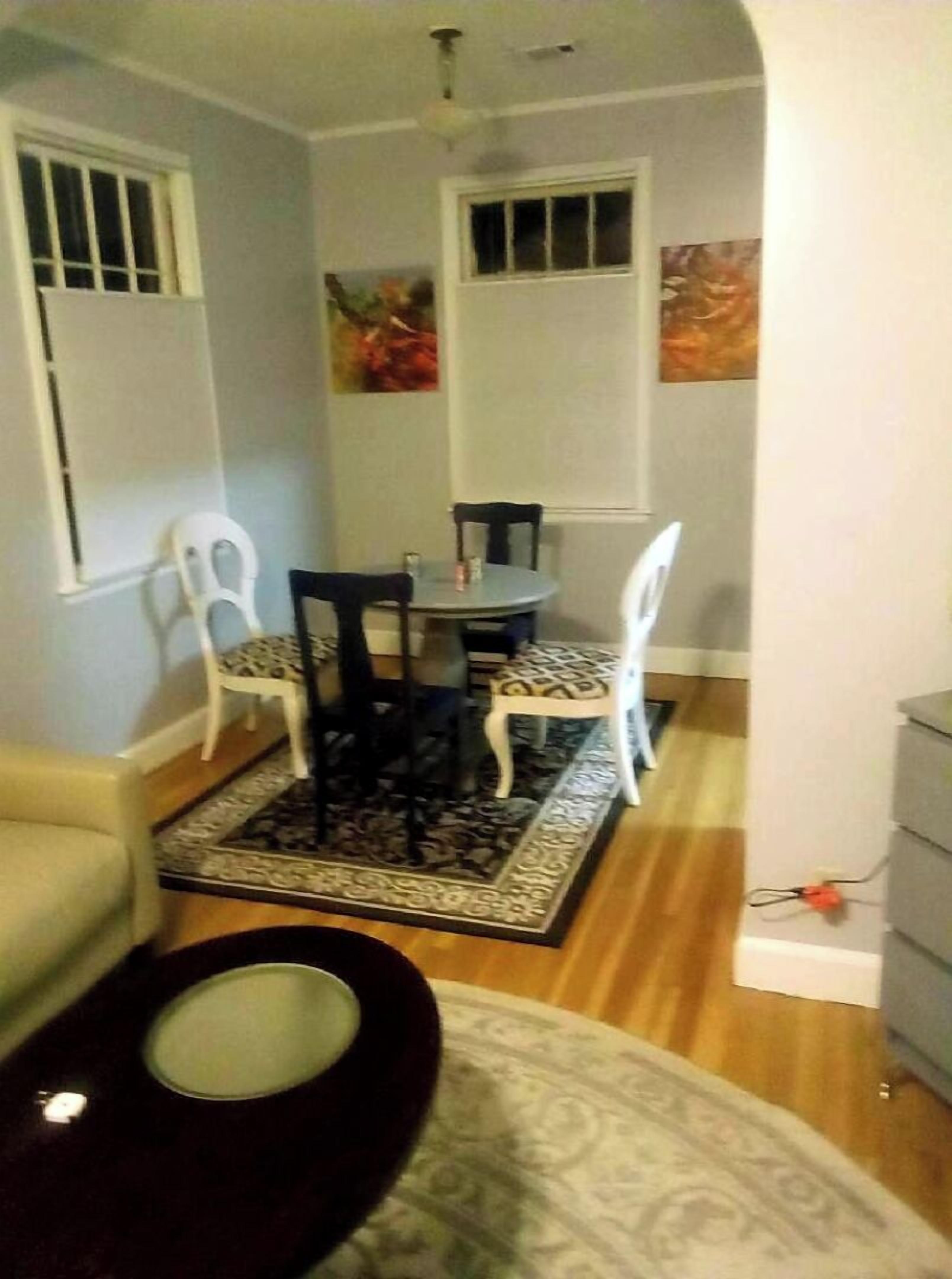 A dining area with a round table and four chairs, a small rug, and a ceiling fan.