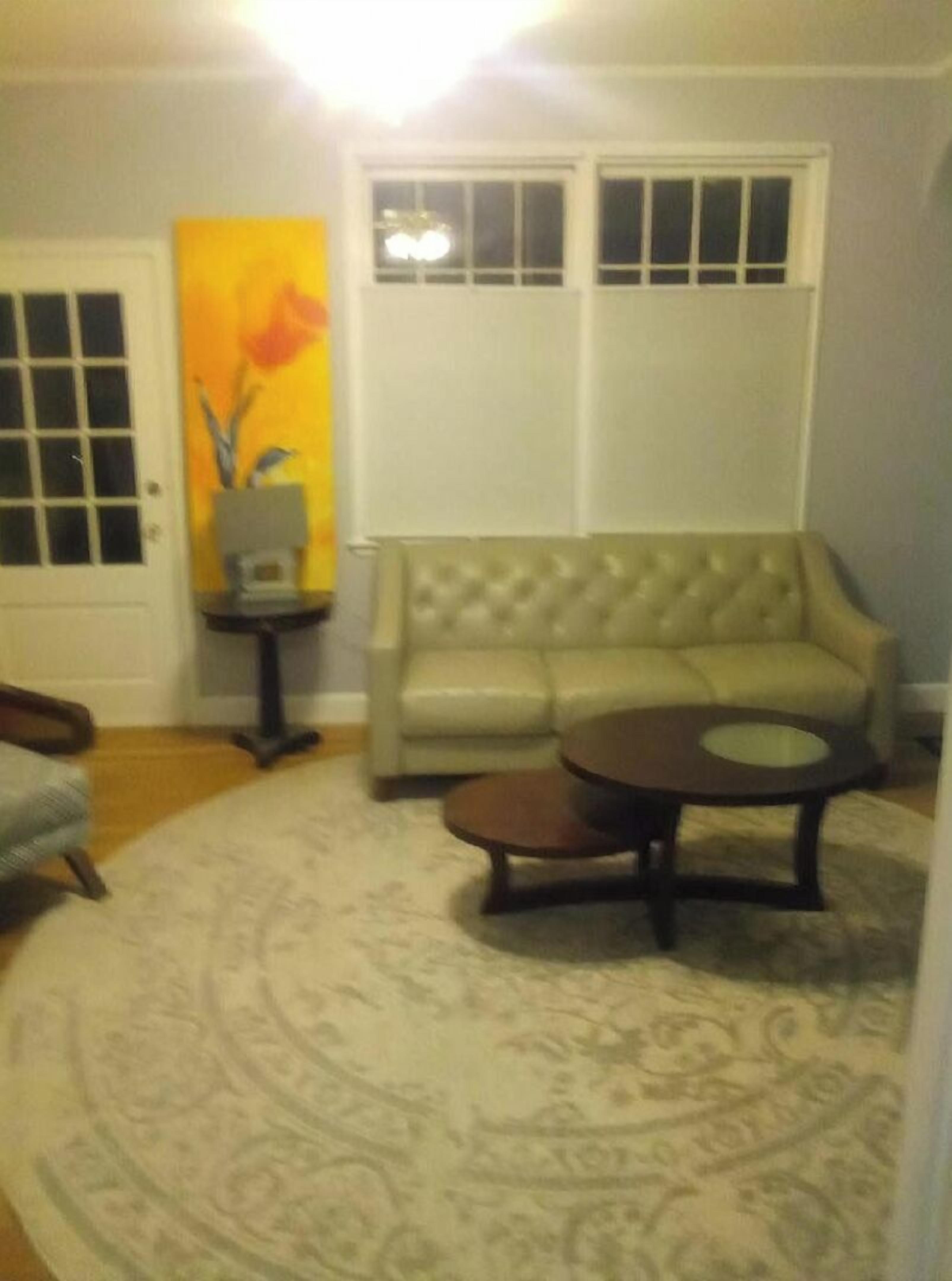 A living room with a beige sofa, a round coffee table, and a patterned rug.