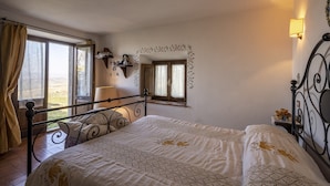 Une chambre à coucher avec un lit, une fenêtre avec des rideaux, une table de chevet et un miroir fixé au mur.