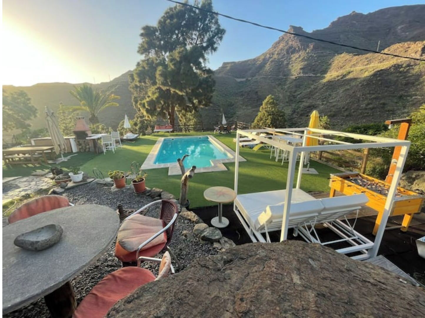 Un jardin avec une piscine, du mobilier d’extérieur et une vue sur les montagnes.