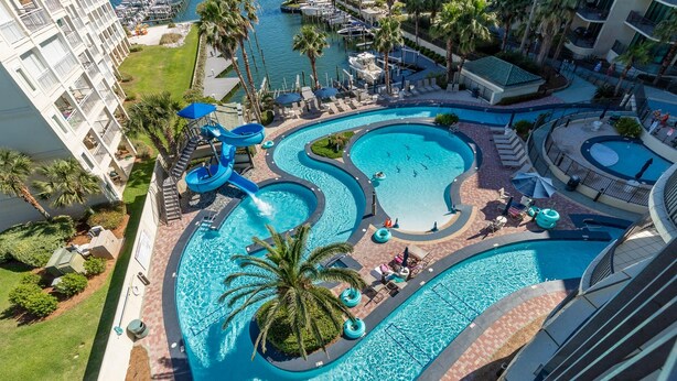 Un complexe hôtelier doté de plusieurs piscines, de palmiers et d’un toboggan aquatique.