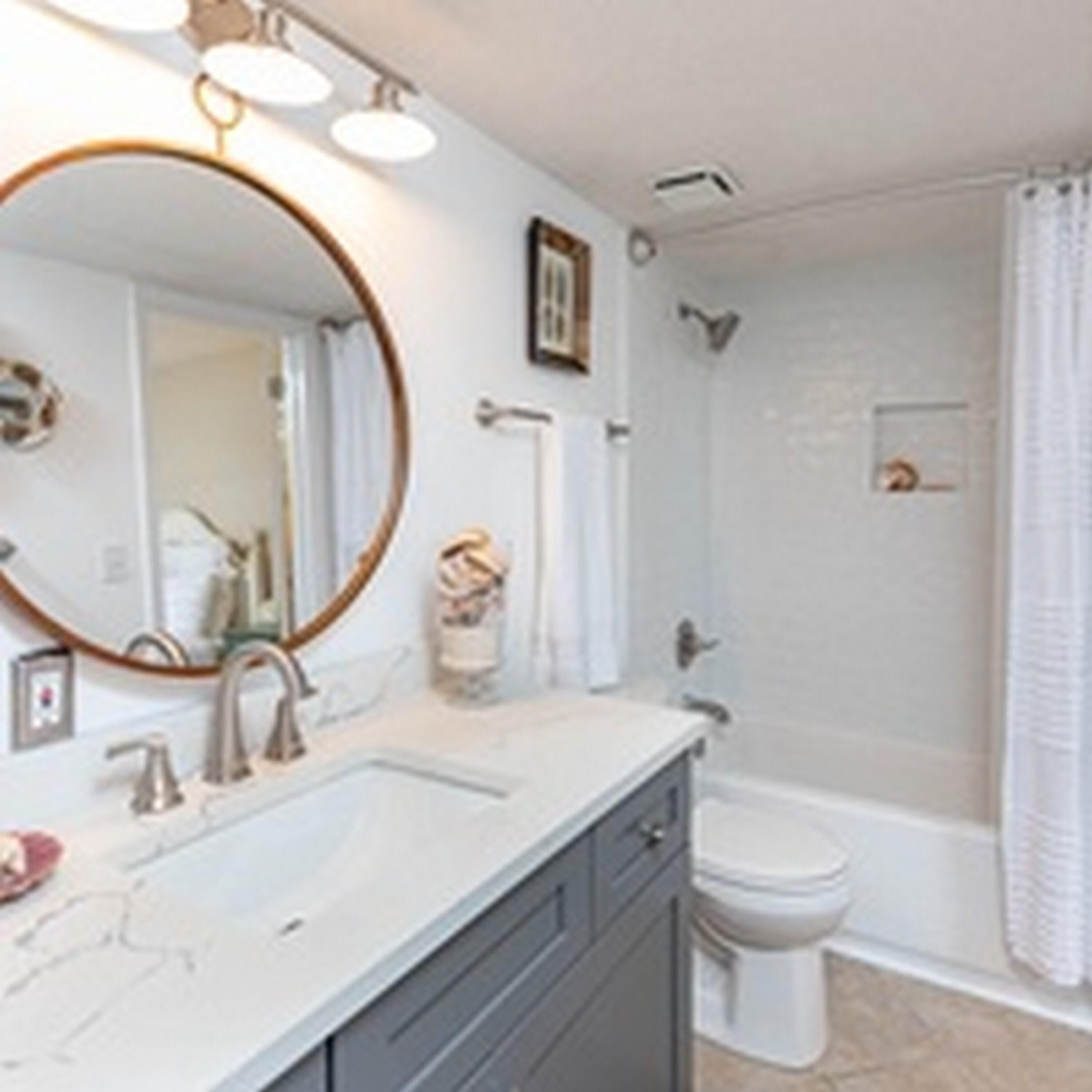 A bathroom with a large mirror, a sink, a toilet, and a shower.
