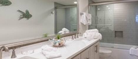 A modern bathroom with a large mirror, a sink, and a shower area.