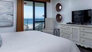 A bedroom with a large bed, a ceiling fan, a TV, and a view of the ocean through a sliding door. - Phoenix VI by Brett Robinson Vacations (Orange Beach)