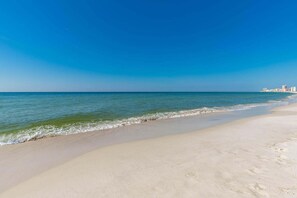 Een strand met helderblauw water en een zandstrand.