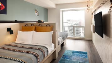 Un dormitorio con cama, un sofá pequeño, una ventana y un televisor.