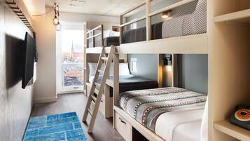 Une chambre avec un lit superposé, une télévision, une échelle et un tapis bleu.