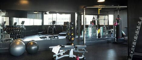 A gym with exercise equipment, a punching bag, and a mirror reflecting the space.