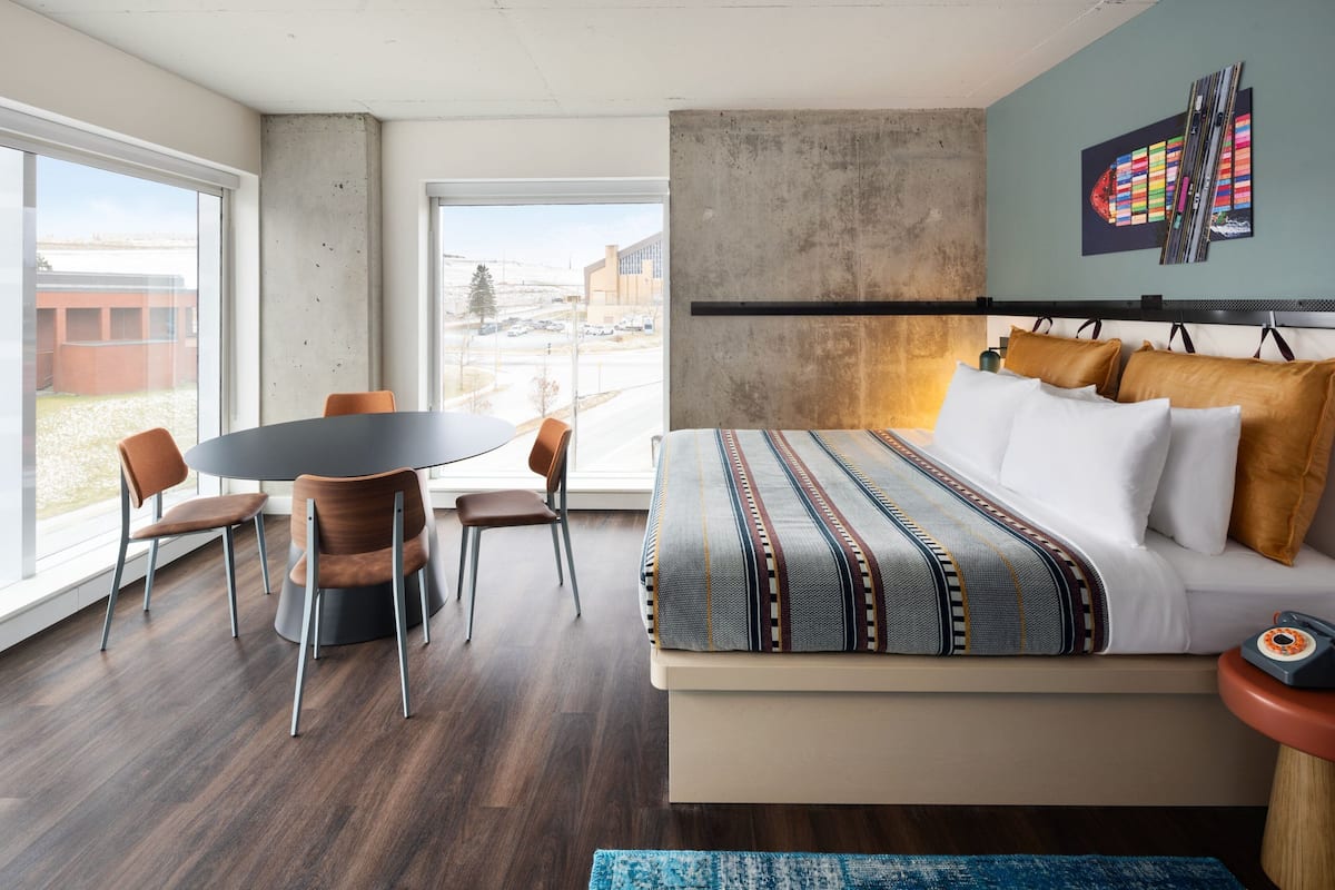 A modern bedroom with a large bed, a dining table, and chairs.