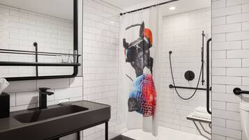 A modern bathroom with a black sink, white tiled walls, a shower with a transparent curtain, and a black towel rack.