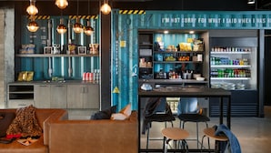 A modern bar area with seating, a refrigerator stocked with beverages, and a map on the wall. - Moxy Halifax Downtown (Halifax)