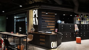 A modern lounge area with a bar, seating, and lockers. - Moxy Halifax Downtown (Halifax)