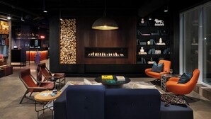 A modern lounge area with a fireplace, seating, and a bar. - Moxy Halifax Downtown (Halifax)