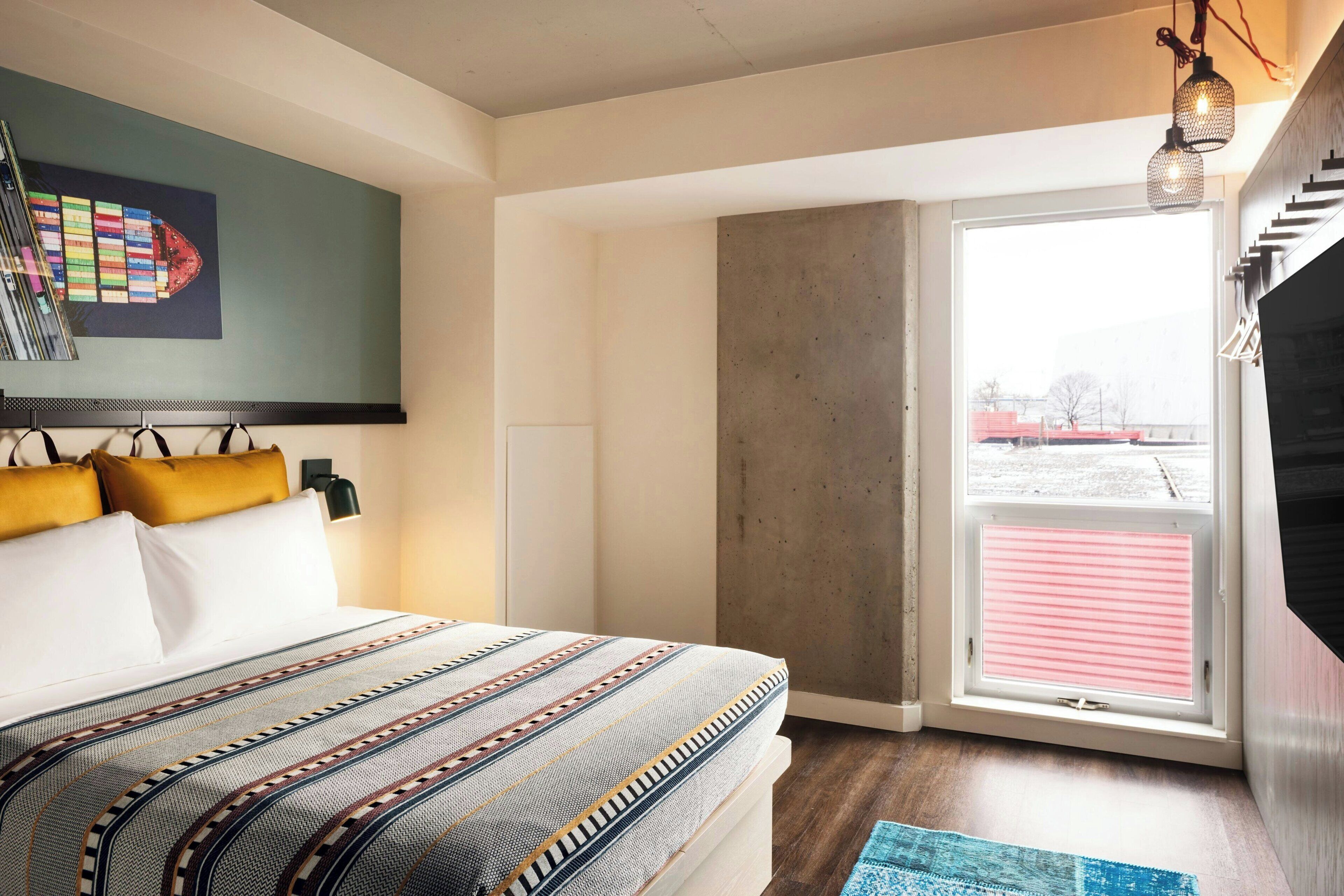 A modern bedroom with a large bed, a view through a sliding door, and a mounted television.
