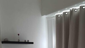 Une chambre moderne avec un lit, un petit bureau et une fenêtre avec des rideaux.