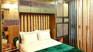 A hotel room with a bed, a mirror, and a wardrobe. - Where Every Sunset Tells a Story Porto Said Chalet (Al-Manasrah)