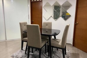 A dining area with a round table and four chairs, a wooden door, and a wall-mounted mirror. - Areia Beach - Pozos Colorados - Santa Marta - Colombia (Santa Marta)